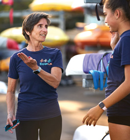 A woman wearing a RowLA t-shirt talks with a younger woman